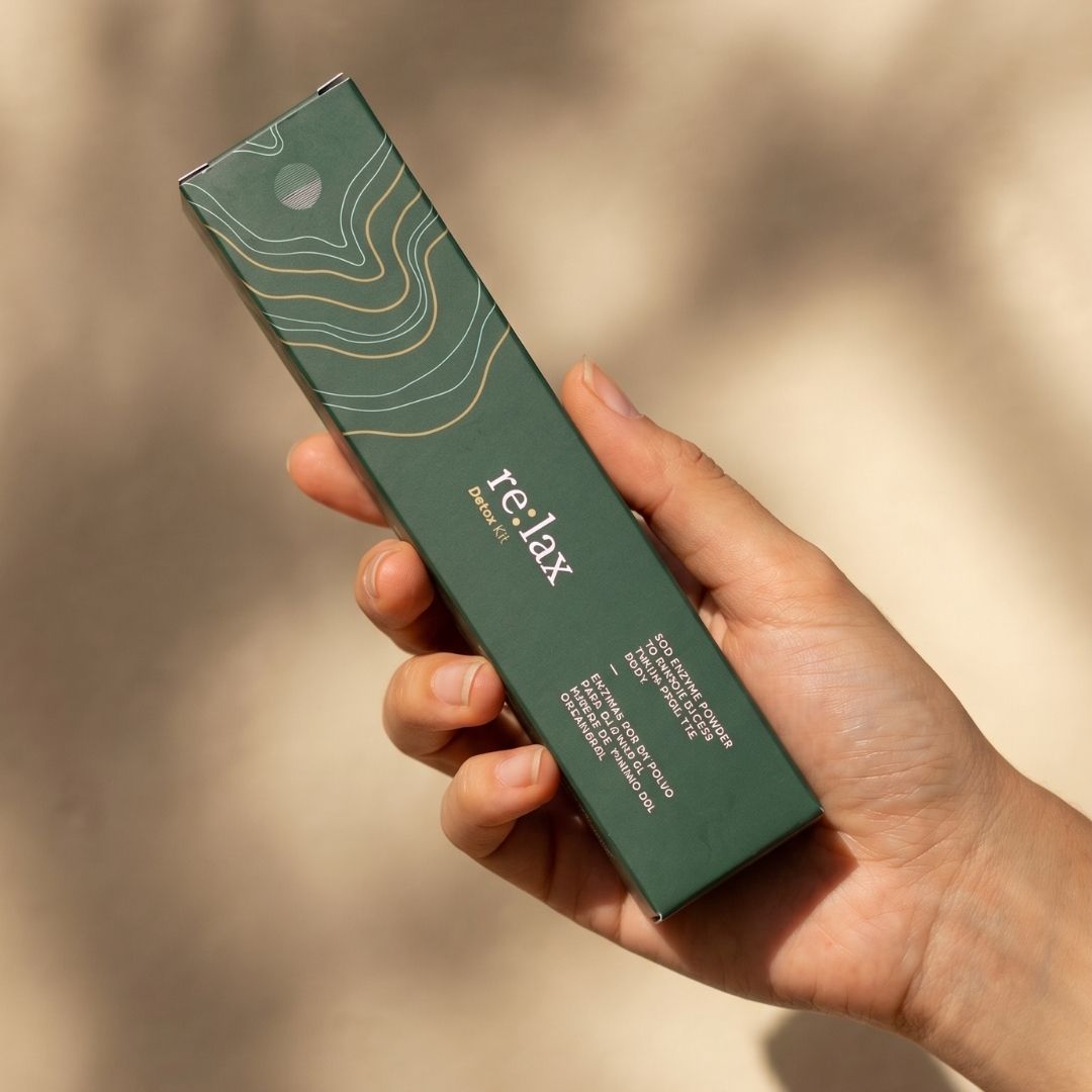 A hand holding the re:lax carton in warm daylight
