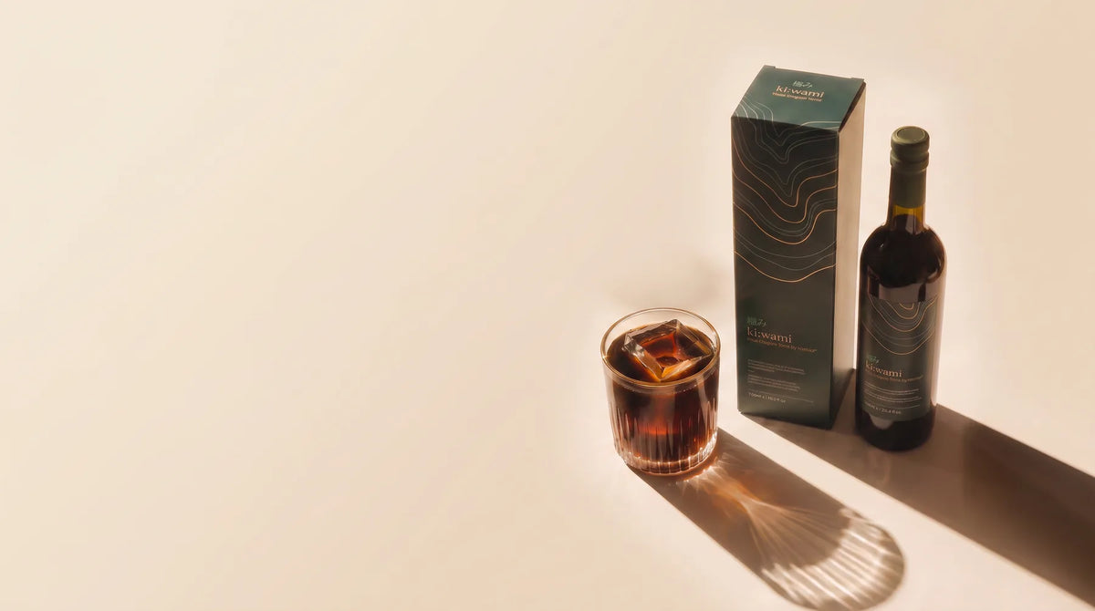 A ki:wami bottle beside its box on a cream surface.
