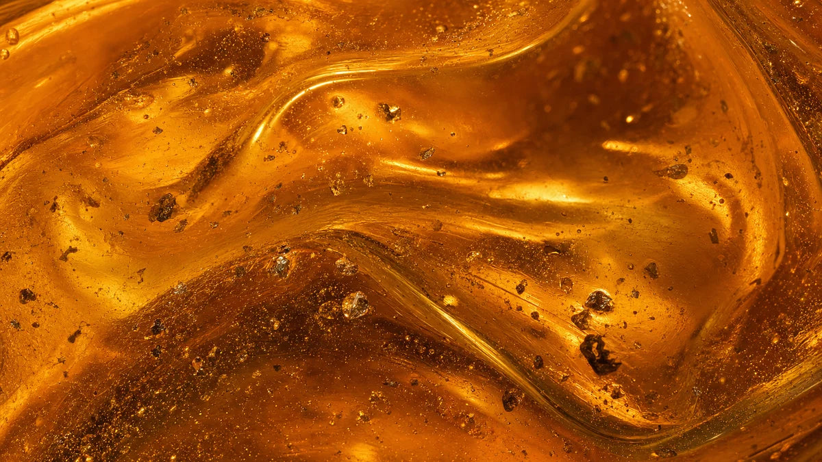 Thick golden-amber mineral concentrate lit from behind, swirling slowly