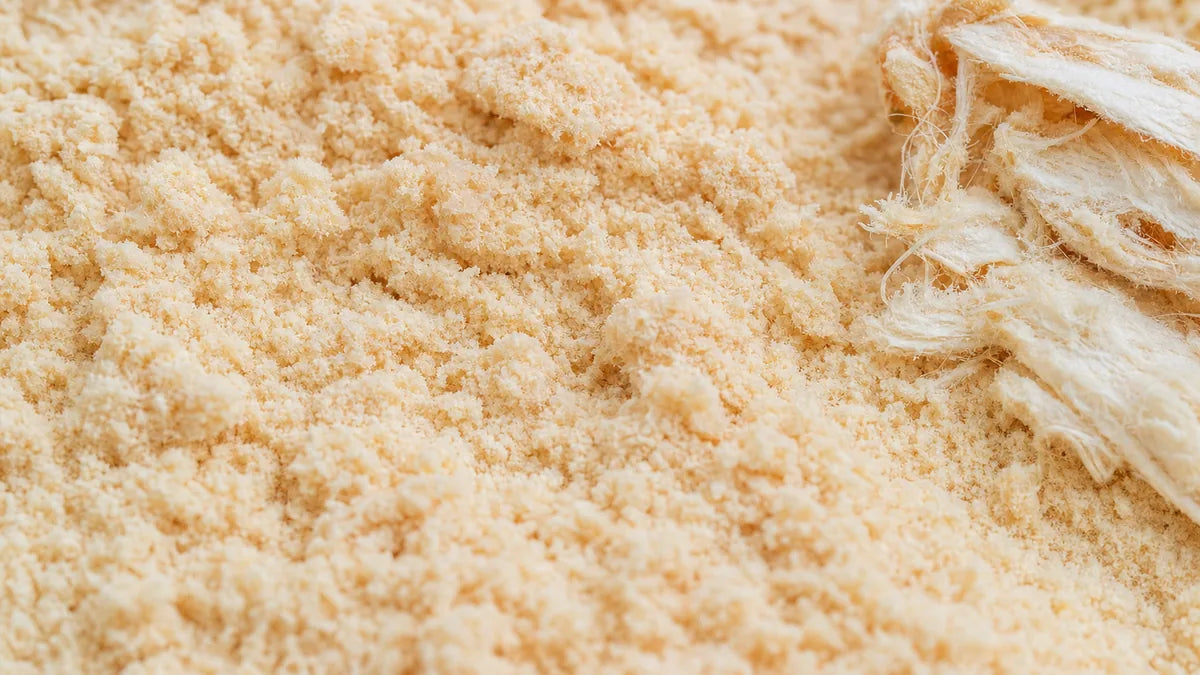 Una macro cercana de polvo de fruta de baobab de color crema pálida con un trozo de pulpa fibrosa