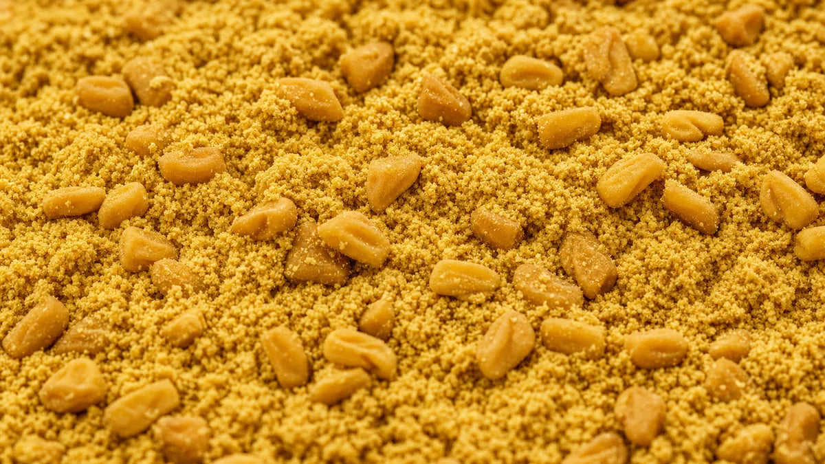 Una macro cercana de polvo de fenogreco dorado esparcido con semillas angulares enteras