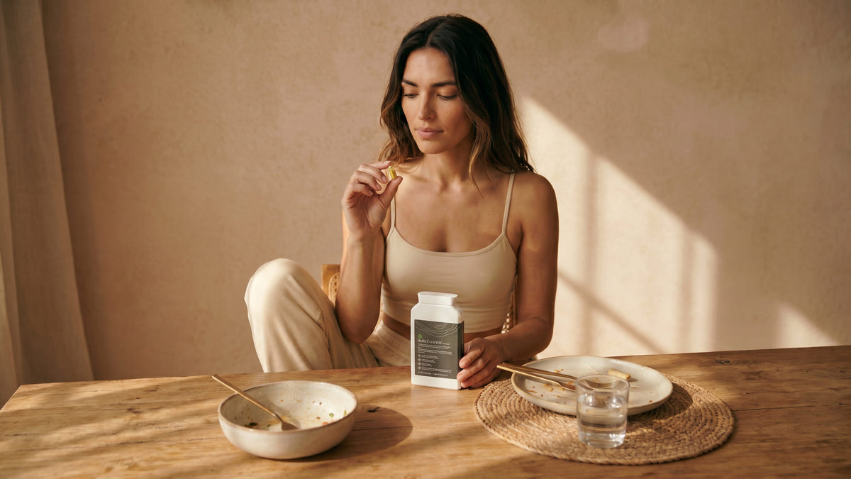 nutri:zyme® capsules beside a plated meal at the table