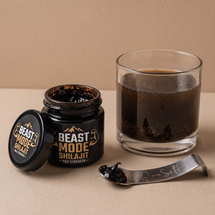 Dark conventional shilajit resin beside a glass of cloudy water with visible sediment.